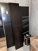 Disassembled Ikea Kallax bookcase panels stacked against a wall showing front surfaces and some shelves wrapped in plastic.