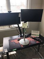 Wide view of both monitors on stand with webcam, vented device, lamp arm and desk mat