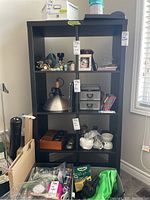 Full front view of black IKEA bookshelf with four shelves containing various miscellaneous items.