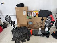 Overall view of lot showing floor mats, metal brackets, cleaning products, storage bag and cardboard box