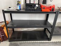 Front view of black metal shelving unit with two shelves showing size and condition.