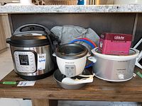 Full set of three kitchen appliances on floor: Instant Pot, Black & Decker rice cooker, Hamilton Beach slow cooker with accessories