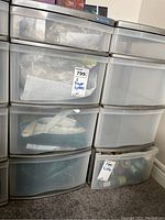 Front view showing two plastic drawer storage containers side by side. The container on left has packing materials visible in drawers; right container appears mostly empty.