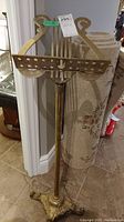 Full view of brass music stand with decorative base and lyre style music holder.