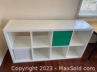 Front view of white cubby shelf with white and green fabric baskets in two compartments