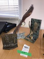 Photo showing the large eagle figurine with outstretched wings, bronze-tone bookend with relief, and green marble eagle bookend on a wooden table.