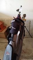 Full view of Nike golf bag containing clubs and featuring Coors Light pocket with black Callaway hat on top.