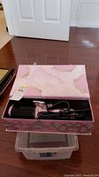 Pink Aria hair dryer brush with marble design in open pink box on wooden floor.