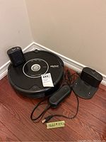 iRobot Roomba 551 vacuum with docking station and power adapter on wooden floor corner