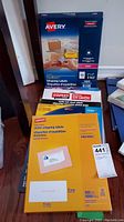Two unopened Avery shipping label boxes standing on the floor, one on top of the other, showing brand and label details.