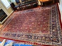 Full view of rug laid out on hardwood floor showing overall pattern and border.