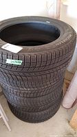 Stack of four Michelin X-Ice tires showing tread pattern and sidewall with tire size label 215/55 R17