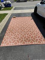 Full view of the outdoor rectangular area mat laid out on driveway, showing overall geometric pattern and size.