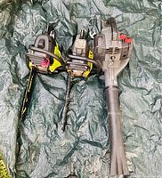 Top view of gas leaf blower and two Ryobi chainsaws on a green tarp showing the entire lot