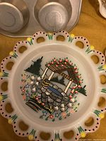 Hand painted ceramic plate with wishing well and floral scalloped edge detail.