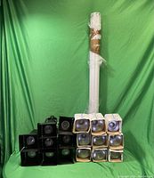 Eight black Microlight LED track lighting fixtures stacked on left, and twenty boxed LED bulbs on right in front of white wrapped long items.