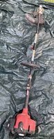 Full length view of Toro grass trimmer showing straight shaft, loop handle, and trimmer head with guard placed on tarp surface.