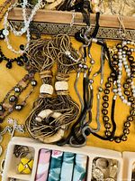 Overview of assorted beaded necklaces in various colors and materials with part of the jewelry box visible