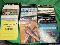 Photo of 35 vintage vinyl records arranged in stacks showing a variety of album covers and titles, indicating good condition.