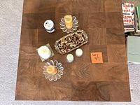 Top down view of the square wood patterned coffee table top with six candles and potpourri tray arranged on it.