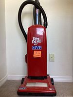 Front view of a red Dirt Devil MVP upright vacuum cleaner with a black hose and visible branding.