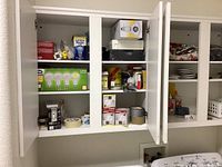 Cabinet with boxed LED light bulbs, rolls of tape, and glue bottles.