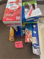 Photo showing assorted boxes and packages of storage bags, foil, parchment paper, and plastic wrap on a flat surface.