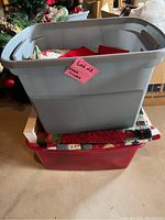 Two plastic bins stacked, labeled 'Lot 23 Xmas Linens' containing linens for Christmas decoration or table setup.