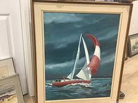 Full view of the framed painting showing a red and white sailboat on the water under a cloudy sky.
