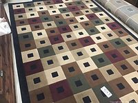 Full view of the carpet showing the multicolor square pattern with black border on the floor.