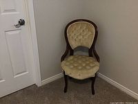 Full view of vintage wooden framed chair with tufted upholstery in beige fabric.