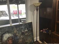 Full view of the floor lamp next to furniture and painting showing the lamp height and glass shade.
