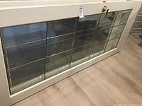 Full view of the French door laid flat on the floor showing white painted frame and beveled glass with brass panes.