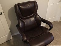 Brown bonded leather office chair with padded backrest and armrests in a room, placed near a white door.