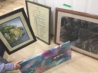 Four pieces of art together: three framed prints and one held canvas
