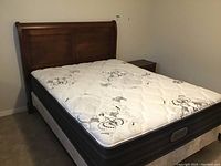 Queen bed frame with floral patterned mattress (not included) placed on the bed frame, wood headboard with panel design.