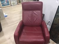 Front view of the red leather recliner chair showing the backrest, armrests, and seat area, highlighting its leather material and condition.