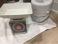 Photo of the Hanson food scale with a white plastic tray and the Braun juicer side by side on a white cloth.