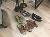 Five pairs of ladies shoes arranged on a floor showing different styles and colors