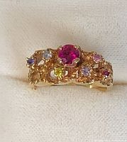 Front view showing center pink round stone and small colored accent stones on decorative gallery
