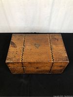 Top view of antique wooden box showing decorative zigzag inlays and central heart-shaped inlay with patina and wear marks.