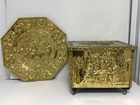 Front view showing octagonal brass repousse wall plate and closed firewood box with brass repousse panels