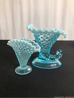 Two blue and white hobnail vases - cornucopia style and fan style seen together from the front.