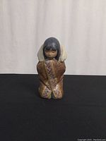 Front view of Lladro Arctic Winter porcelain figurine showing facial features, cloak design and posture kneeling.