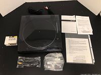 Top view of turntable closed with cables and manuals bundled around, also small box of stereo pre-amp.