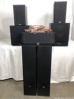 Full set of speakers and subwoofers arranged on table with speaker cables on top