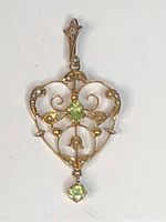Front view of vintage heart-shaped pendant showing gold-tone metalwork, seed pearls, and peridot stones.