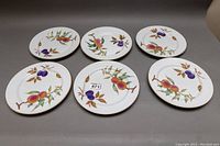 Six Royal Worcester Evesham dinner plates arranged flat showing fruit designs on white porcelain with gold rims.