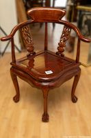Front view of the Chinese rosewood corner chair showing intricate carvings and overall shape.