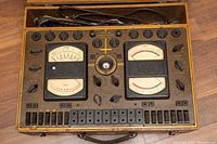 Full top-down view of the Diagnometer showing two analog meters, multiple rotary knobs, slider switches, and circular sockets along the top.